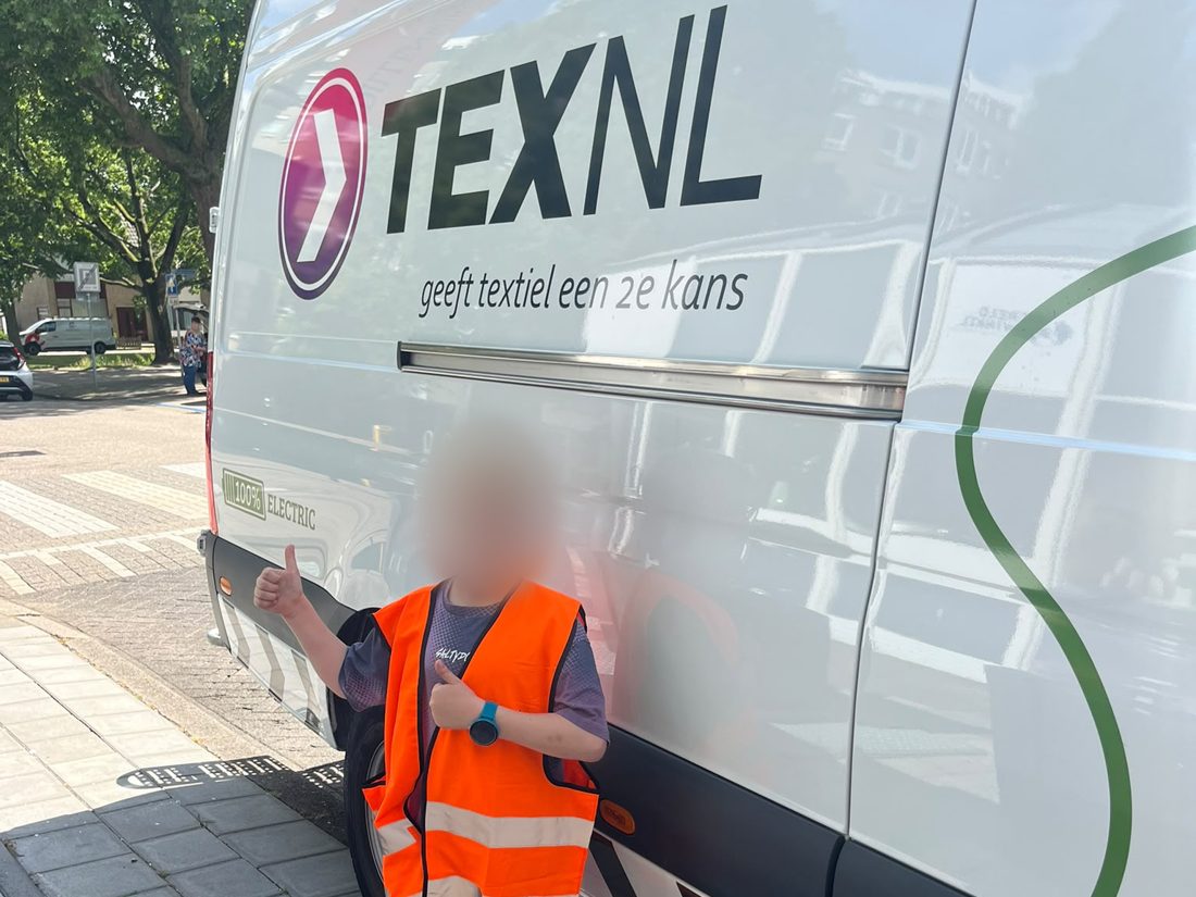 Kind in oranje hesje steekt de duim op bij de TexNL-bus